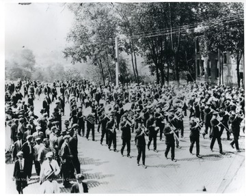 Marching band passes people lining the streets.