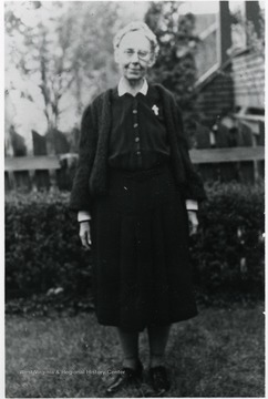 Julia A. Lakey, Director of Scott's Run 1924-1925 standing in front of hedges and wooden fence.