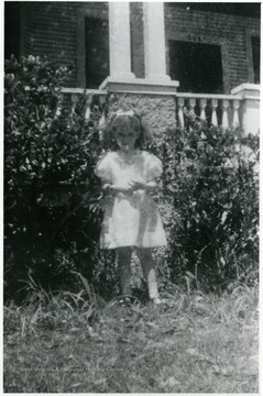 Helen Digit (age five), Luella Digit's daughter, standing in front of building with the number 504 above the door.