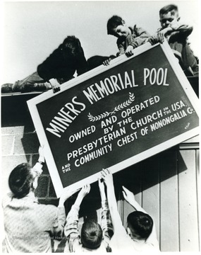 Men putting up sign. 'For information on the Mountaineer Mining Mission See A&amp;M 2491 (S.C.).'