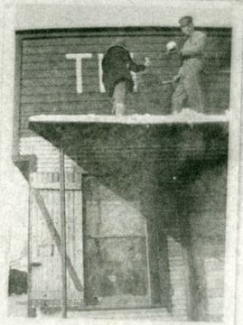 Painting the Shacks name on the building are Miss Behner and George Lay. She was an early director of the Presbyterian 'Shack'. Later on she became director of the Scotts Run Settlement House near Osage, W. Va., which was a Methodist Settlement house. 'For information on the Mountaineer Mining Mission, See A&amp;M 2491 (S.C.).'