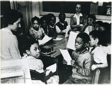 A group of Osage School children in the 1940s and teacher, Mrs. Richard Smith (left hand corner.) Osage School was located in Osage, West Virginia, Monongalia County.  Mrs. Smith may have been visiting the classroom as African-American teachers were employed by the segregated school at this time.For information on the Mountaineer Mining Mission see A&M 2491 (SC).