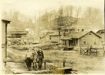 Three boys standing in front of houses. 