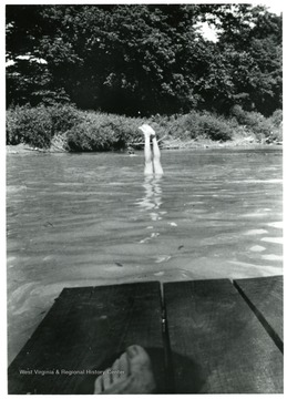 Someone is doing a headstand in the water with their feet sticking out.