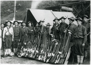 The National Guard stands behind a row of rifles.