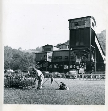 'Gardener cultivating flower bed on lawn in front of preparation plant, Mine No. 98, Consolidation Coal Co., W. Va.' Bituminous Coal Institute, 320 Southern Building, Washington 5, D.C. November 1948.