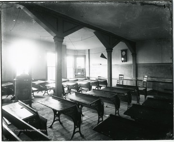 Room with empty desks are empty. Math problems are written on the chalk board.