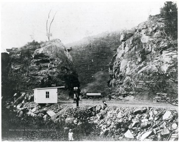 A lady sits on a boulder from the blasting to make Falls Mill Rd. 