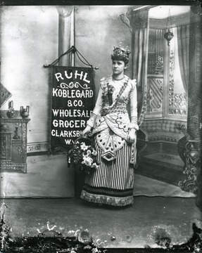 Advertisement for Ruhl Koblegard and Co. Wholesale Grocery, in Clarksburg, West Virginia, featuring a girl wearing an ornate dress and holding a basket of flowers.