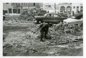 A man is shoveling snow on the corner of Cleveland and Locust Avenue in Fairmont, West Virginia during the big snow storm of 1950.