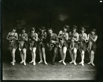 Eight women and one men are playing the saxophone.