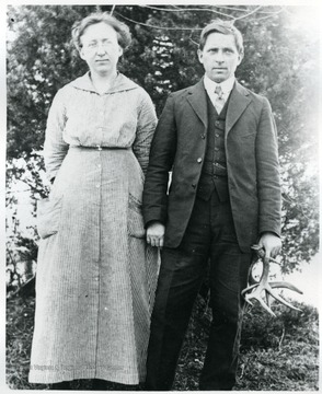 A man holding deer antlers stands next to a woman.