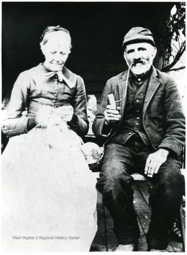 The man smokes a pipe while the women crochets.