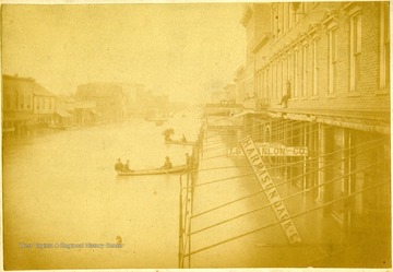 Men in canoes travel on Third Street in Huntington.