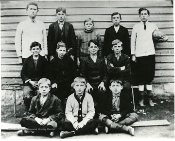 Group portrait of boys.  Boy in back row on right is holding a football.