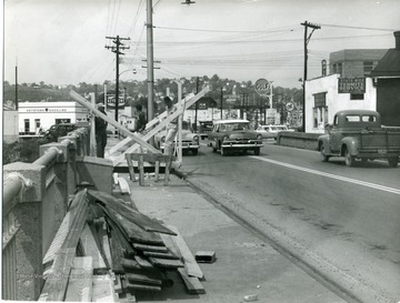 Cars pass as workers repair the University Avenue bridge.