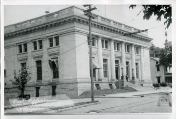 A lady is standing on the steps of the Morgantown Post Office in Morgantown, West Virginia.