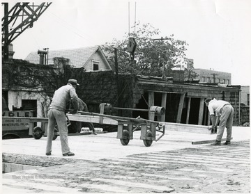 Three men working on the construction of Massullo's and the Mountaineer Sport Shop building on High Street, Morgantown, W. Va.