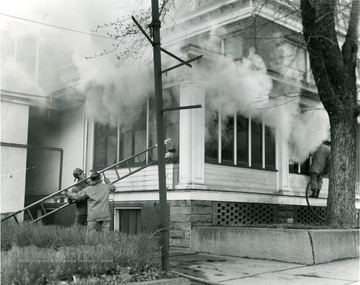 Firefighters working to extinguish fire at the old Elks Club in Morgantown, W. Va. Smoke is rolling out of the windows of the building. 