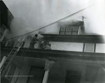 Firefighters working to extinguish fire at a residence located on the corner of Fayette Street and Chestnut Street in Morgantown, W. Va. 