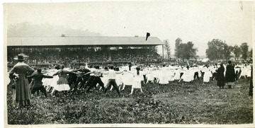 Wheeling Public School students do jumping jacks before a crowd in a grandstand for Field Day.