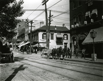 'Very early view of High Street' in Morgantown, W. Va. Horses can be seen pulling wagons. 'Walnut and High Street Odd Fellows on Right Corner.'