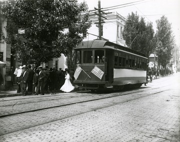 Street car seen here on High Street in Morgantown, W. Va. Groups of people line the sidewalk. 