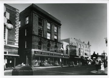 Two people are waiting to cross the street, across from the Five and Dime G.C. Murphy Company Store on High Street in Morgantown, West Virginia.