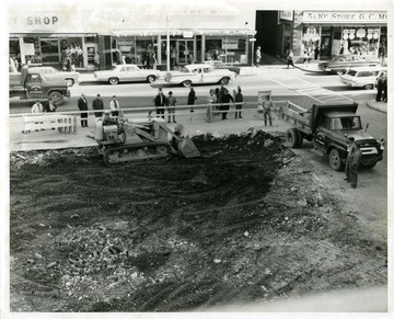 Construction workers are grading the Courthouse Square on High Street in Morgantown for rejuvenation. Montgomery Ward and G.C. Murphy Department Stores are across the street.