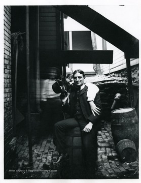 Two men are sitting on a barrel in an alley in Morgantown, West Virginia.