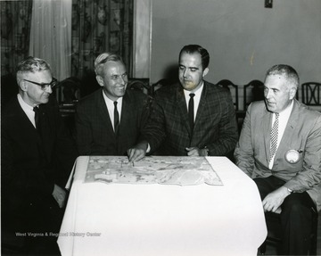 Members of the Morgantown Kiwanis Club look over a map. Some of the men include 'Victor J. Lemke, Foster Mullenax, and Robert Creel'.