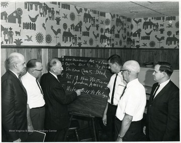 The man writing is Howard Smyth.  The man on the far right is John Pyles.