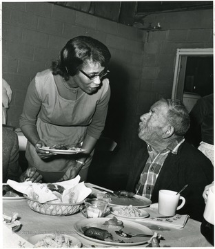 'Yes the dinner was fine.  Now I'll have my ice cream dessert!' A lady chats with a man having dinner.