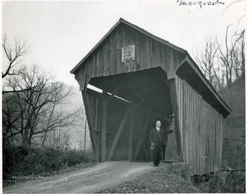 View of man standing at bridge entrance.
