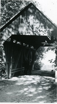 View of two men and dog standing at bridge.
