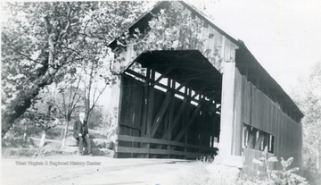 View of man sitting on stones at south end of bridge.