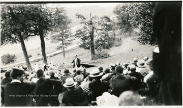 Group seated on a hillside listening to speaker.