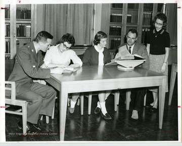 Five people are looking at books in the Rare Books Room, in Wise Library, West Virginia University.