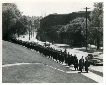 Graduates walk down Beechurst Avenue, across from Stansbury Hall.