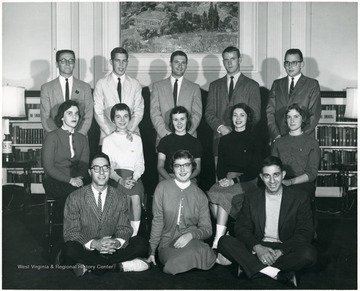 A group of students gathered in front of a fire place in Elizabeth Moore Hall.  Some students are named: Top Row from left to right 1) Unknown 2) Unknown 3) Unknown 4) 'Mike' Oliver 5) Unknown; Middle Row 1) Unknown 2) Barbara Sayre 3) Ruth Ann Walker 4) Carolyn Miller 5) 'Vickie' Vickers; Bottom Row --all unknown.