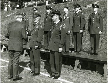 'Major General Ralph W. Zwicker presents Dept. of Army Civilian Award of Appreciation to Dr. Irvin Stewart, former University President at brigade ceremony on drill field.  President Stahr in civilian clothes on reviewing stand.'