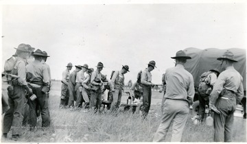 Cadets line up with utensils in hand to be served a meal.