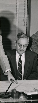 A photo clip from West Virginia Newspaper Pub. Co. "Let's Get Acquainted" section shows president Irvin Stewart at desk discussing blueprint in front of him with others.