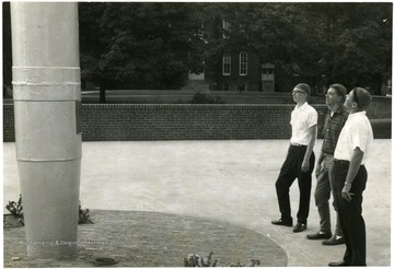 Three unidentified students observe the U.S.S. West Virginia mast. 