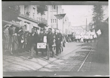 A thanksgiving day parade: students are holding a sign of 'W&J' while they march the street.