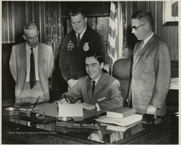 2nd from left standing behind Gov. is Robert Kelly