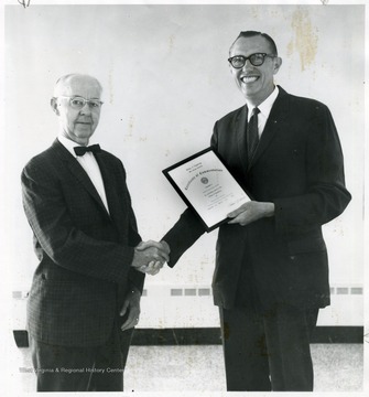 Cherster Arents (right) being presented with a certificate by Harold Cather (left).