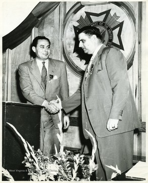 A photograph of Henry Kiser (right) shaking hands with Eugene A. Carter (left).