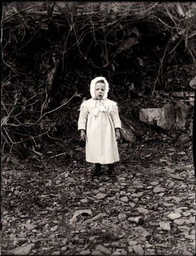 A portrait of child standing on what appears to be a dry river bed.