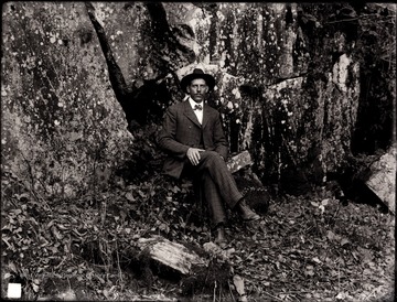 A portrait of man sitting by rock ledges.